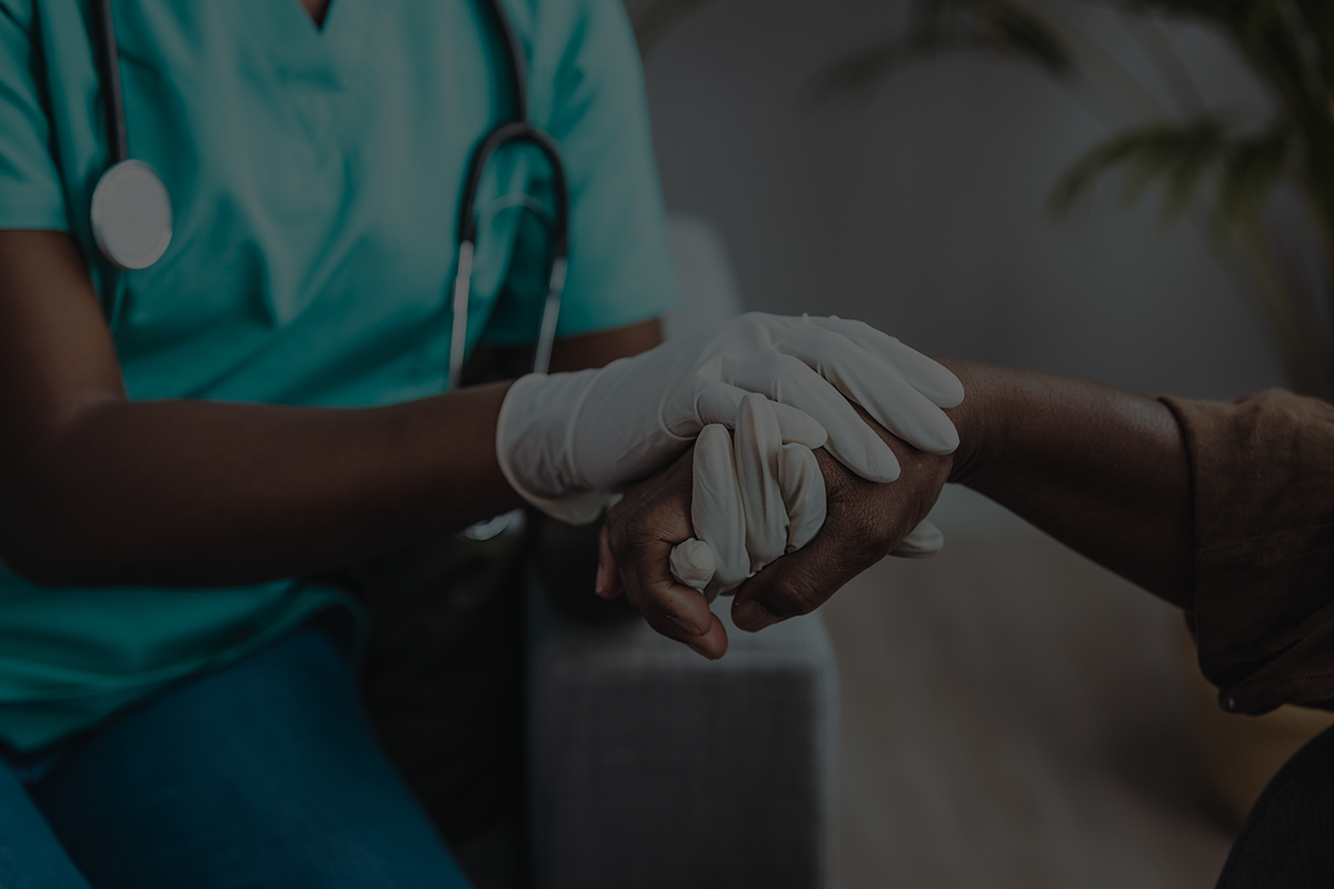 A health care provider's hands holding a patients hand.